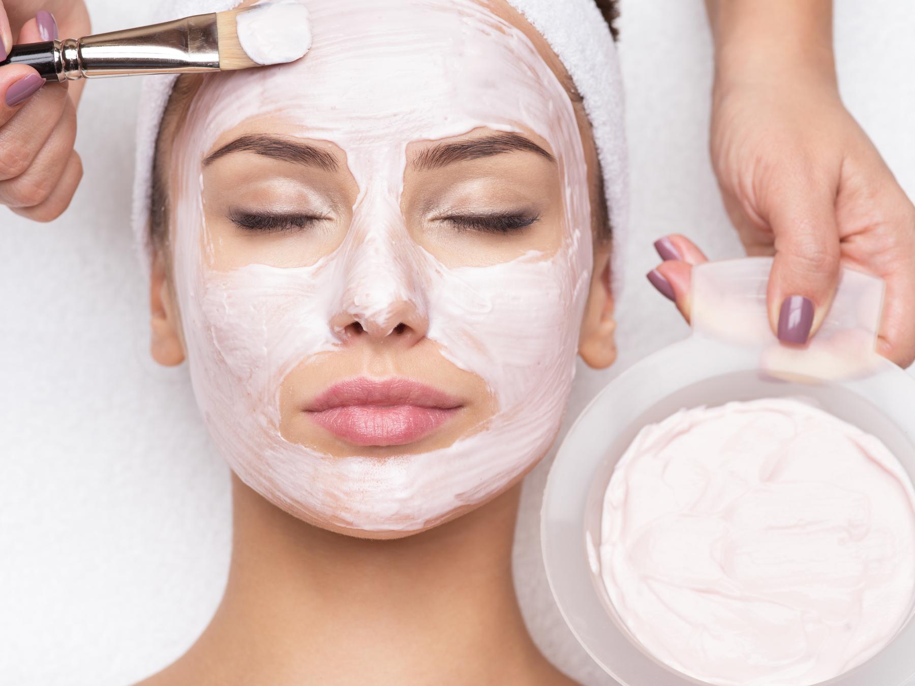 woman receiving facial mask in spa beauty salon